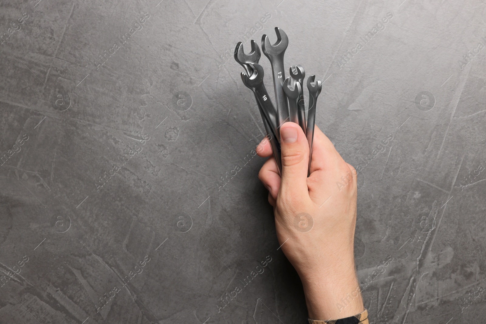 Photo of Auto mechanic with wrenches at grey textured table, top view