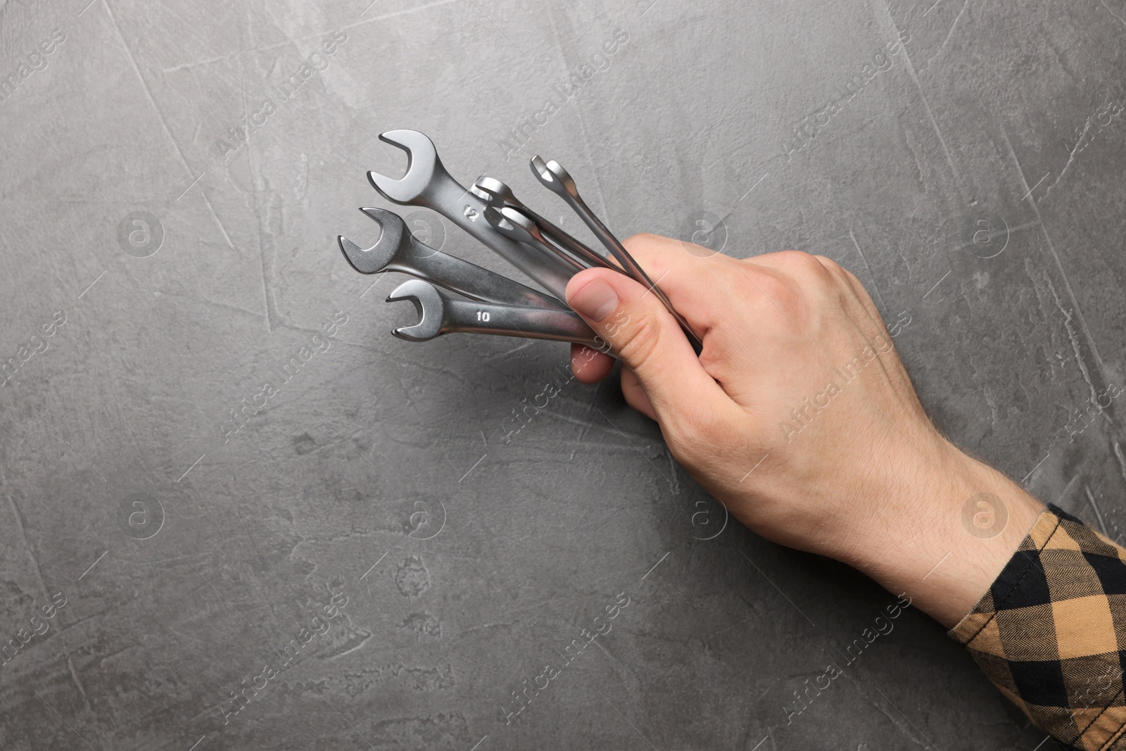 Photo of Auto mechanic with wrenches at grey textured table, closeup