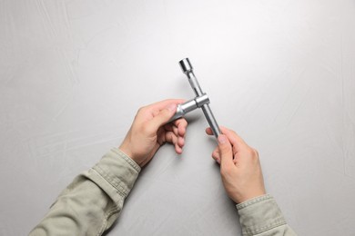 Auto mechanic with torque wrench at light grey textured table, top view