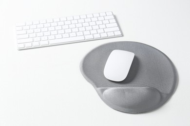 Photo of Keyboard, mouse and mousepad with arm rest on white table. Space for text