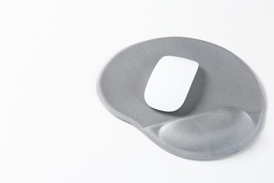 Photo of Mouse and mousepad with arm rest on white table, closeup. Space for text