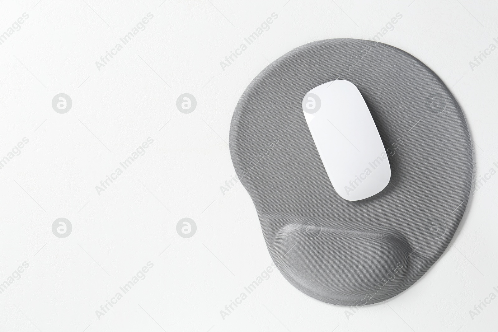 Photo of Mouse and mousepad with arm rest on white table, top view. Space for text