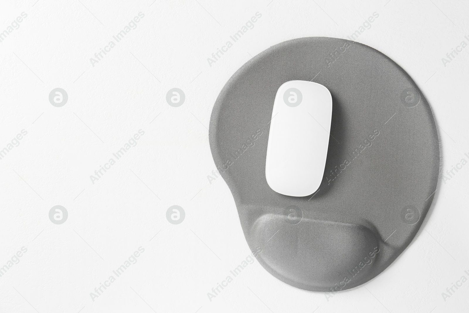 Photo of Mouse and mousepad with arm rest on white table, top view. Space for text