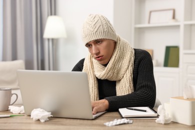 Cold symptom. Young man suffering from fever at desk indoors