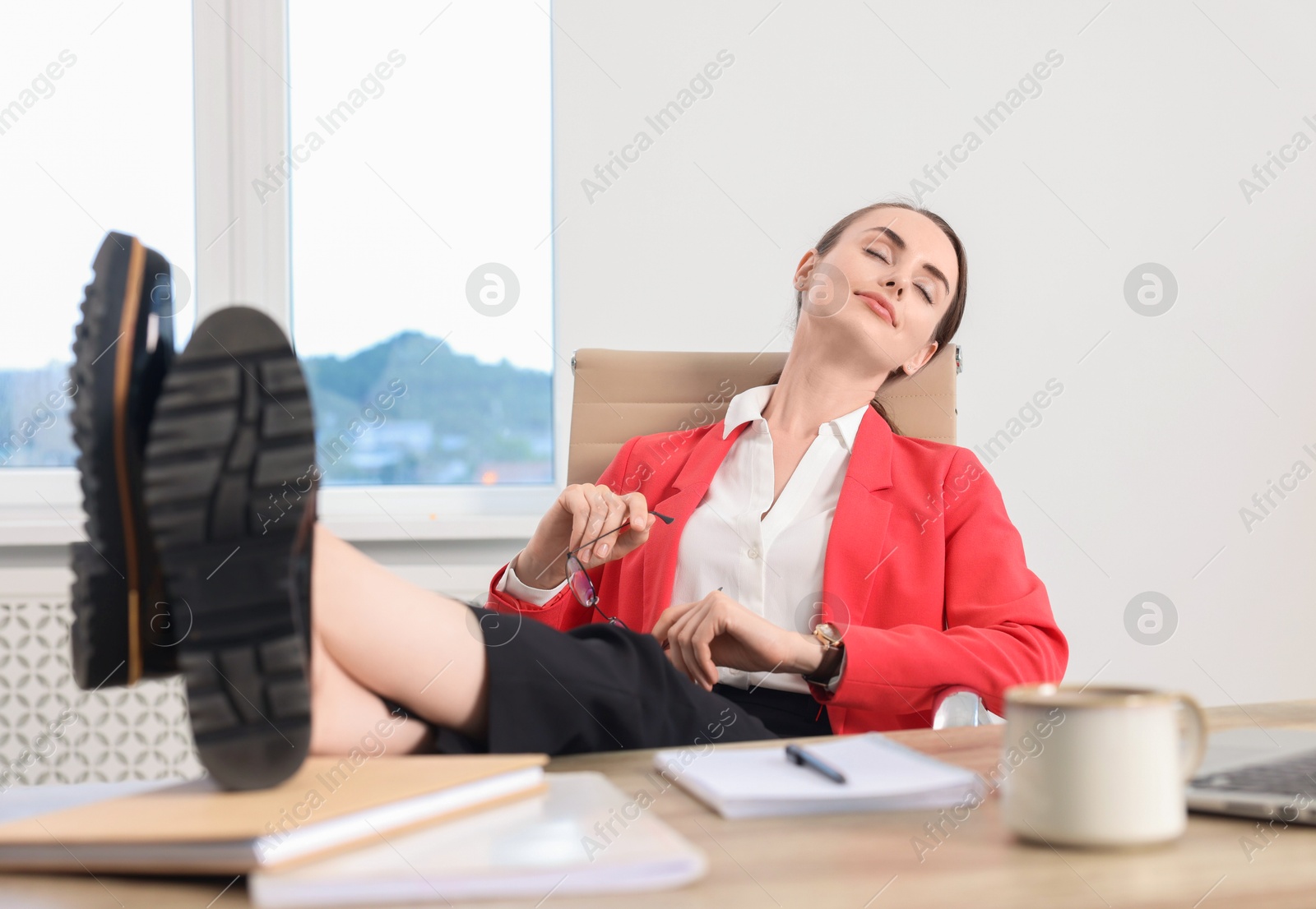 Photo of Beautiful businesswoman holding legs on table in office. Break time