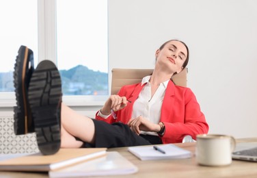 Photo of Beautiful businesswoman holding legs on table in office. Break time