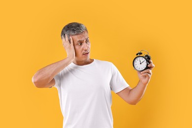 Overslept man with alarm clock on orange background