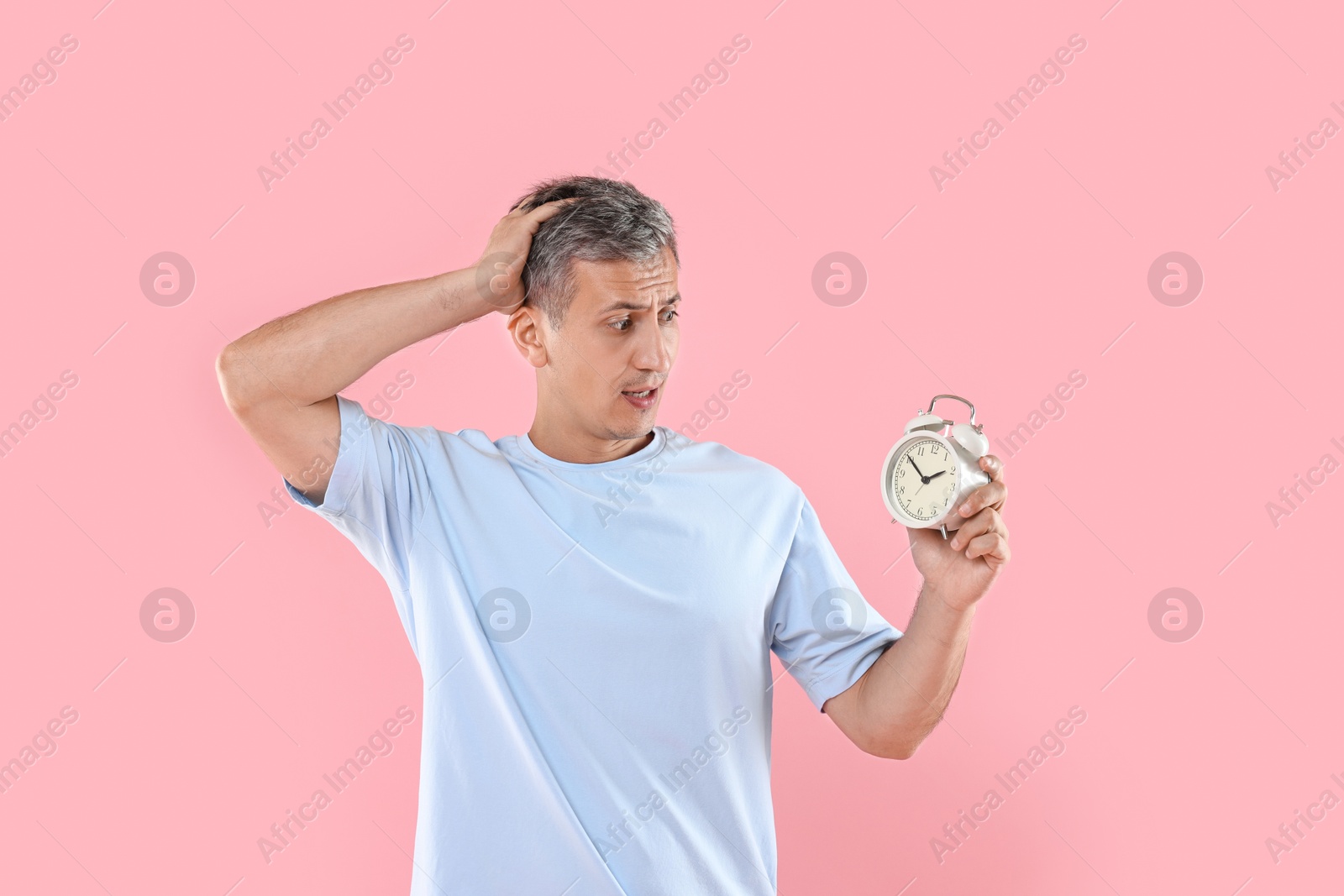 Photo of Overslept man with alarm clock on pink background