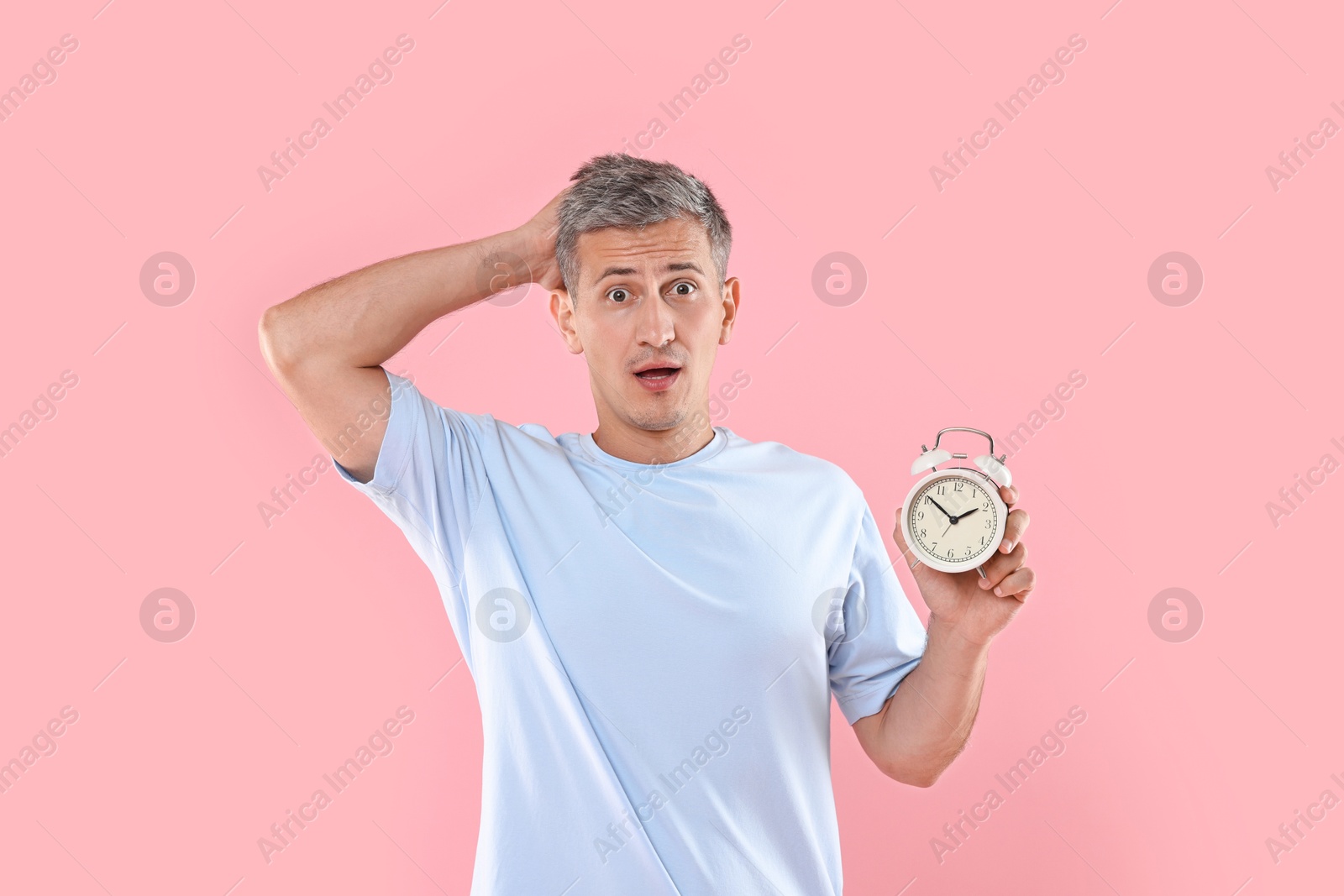 Photo of Overslept man with alarm clock on pink background