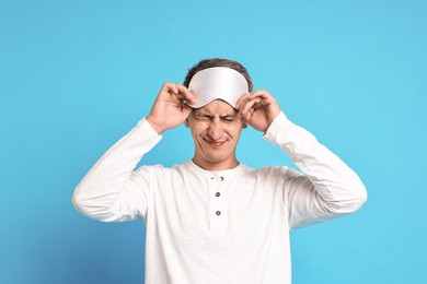 Photo of Overslept man with sleep mask on light blue background