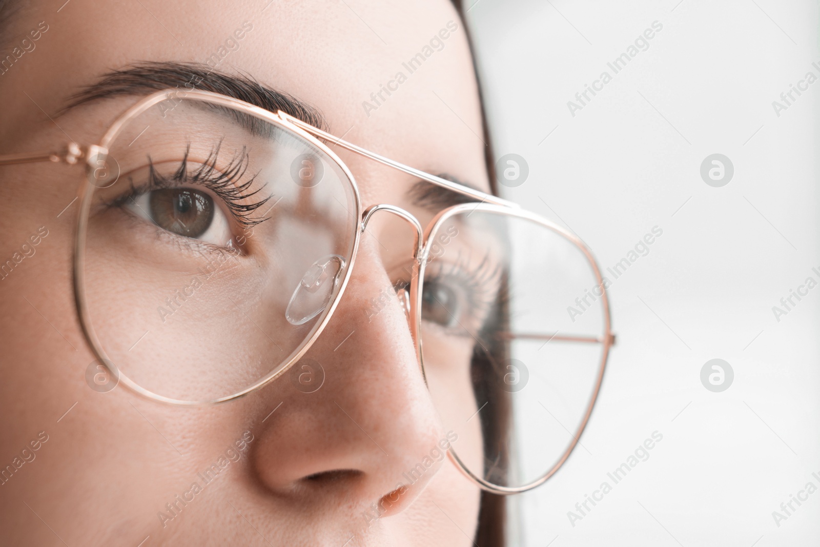 Photo of Closeup view of woman wearing eyeglasses on blurred background