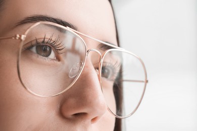 Closeup view of woman wearing eyeglasses on blurred background