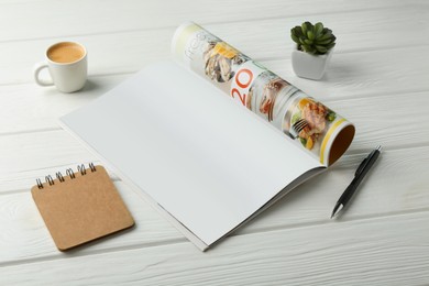 Photo of Open magazine with blank page, coffee, plant and stationery on white wooden table. Mockup for design