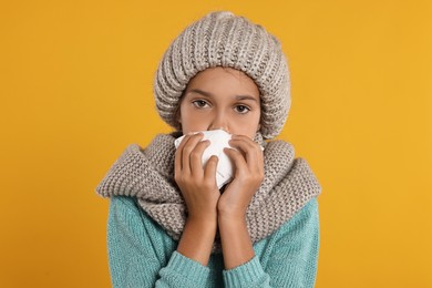 Photo of Cold symptom. Little girl with runny nose on orange background