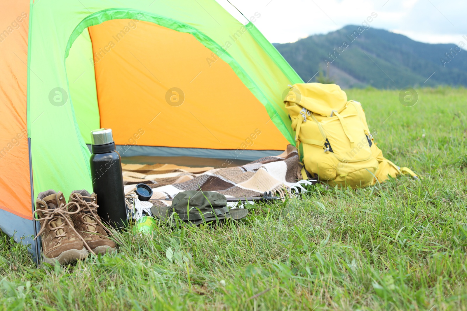 Photo of Tent and backpack on green grass in mountains