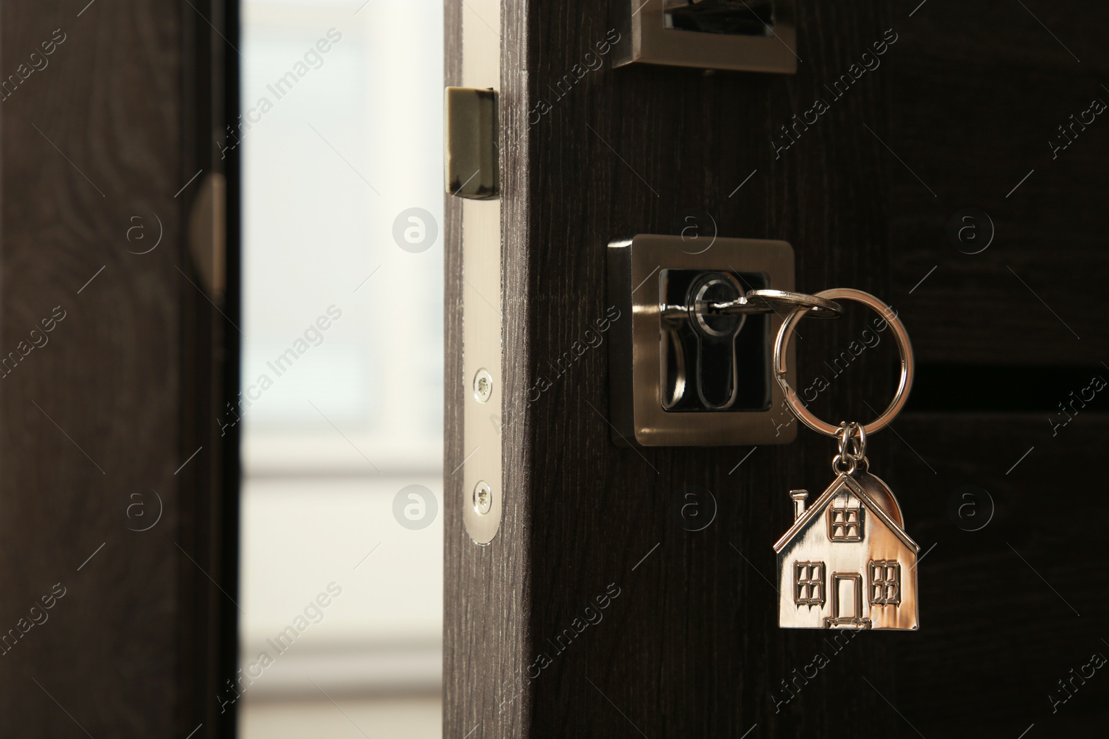 Photo of Open door with key and house shaped keychain, closeup