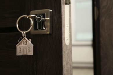 Open door with key and house shaped keychain, closeup