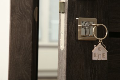 Open door with key and house shaped keychain, closeup