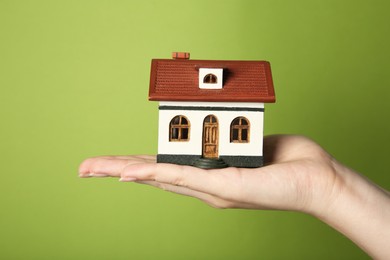 Photo of Woman with house model on green background, closeup