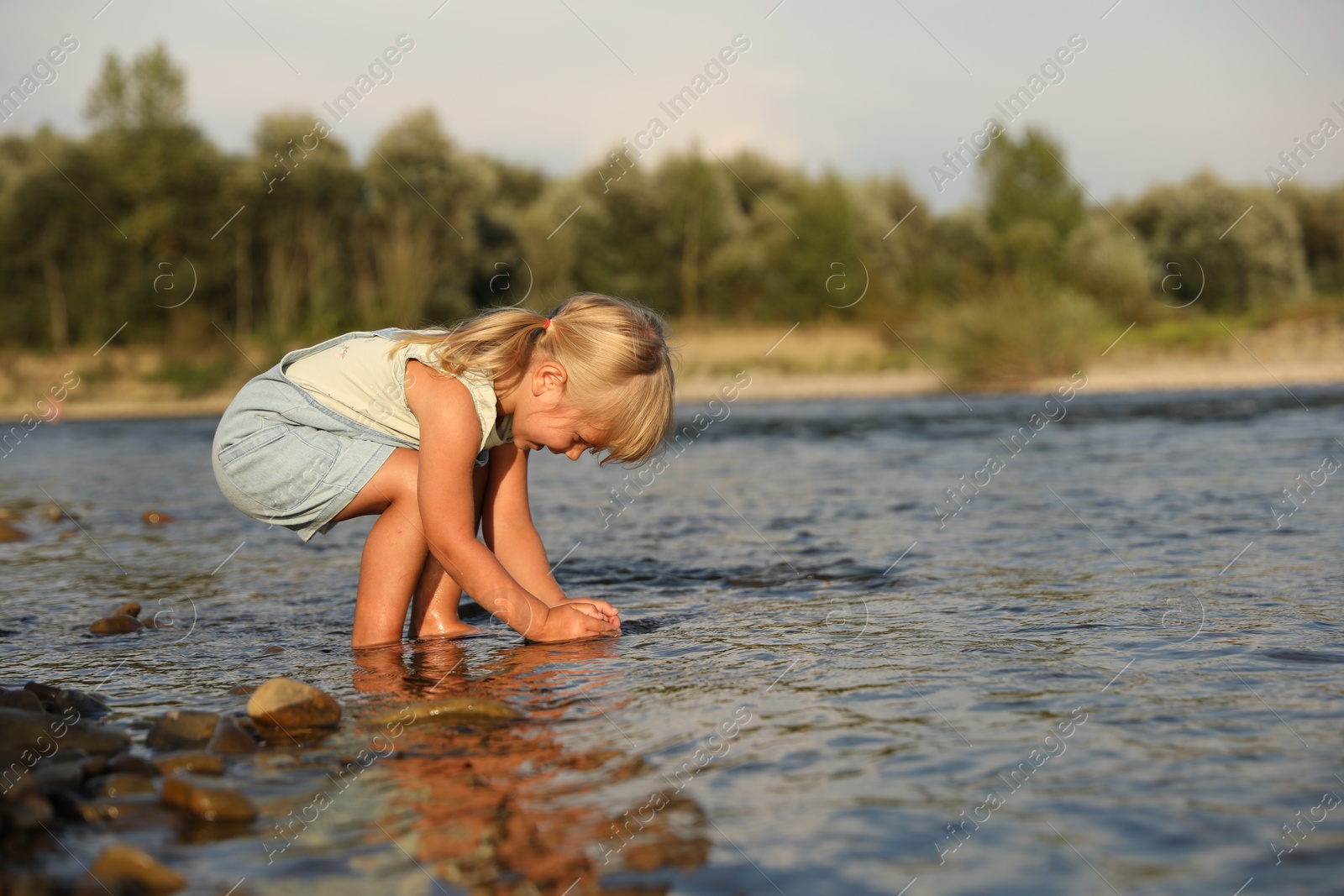 Photo of Cute little girl spending time on river. Child enjoying beautiful nature