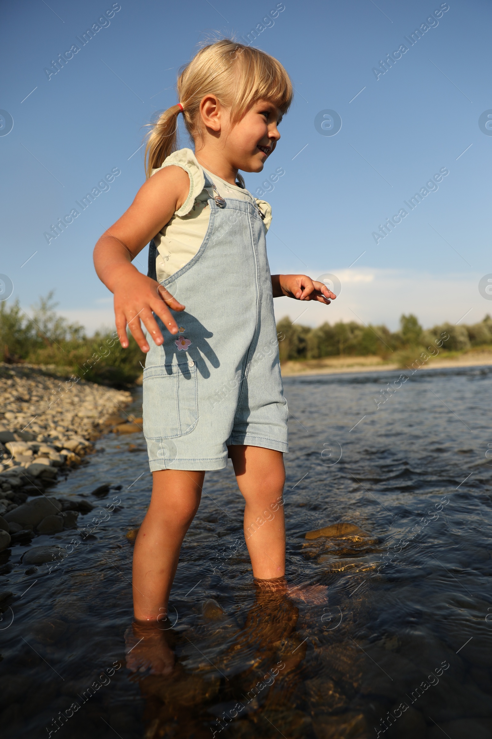 Photo of Cute little girl spending time on river. Child enjoying beautiful nature