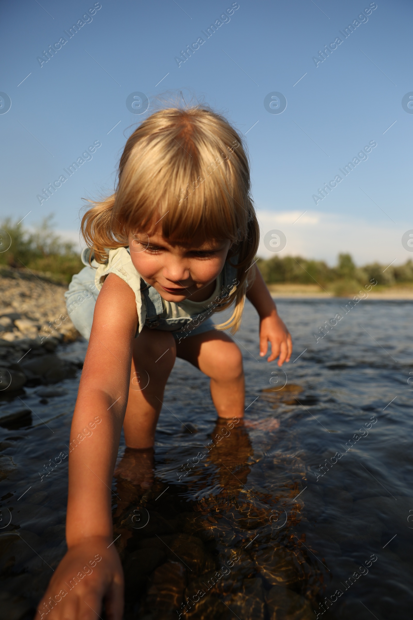 Photo of Cute little girl spending time on river. Child enjoying beautiful nature