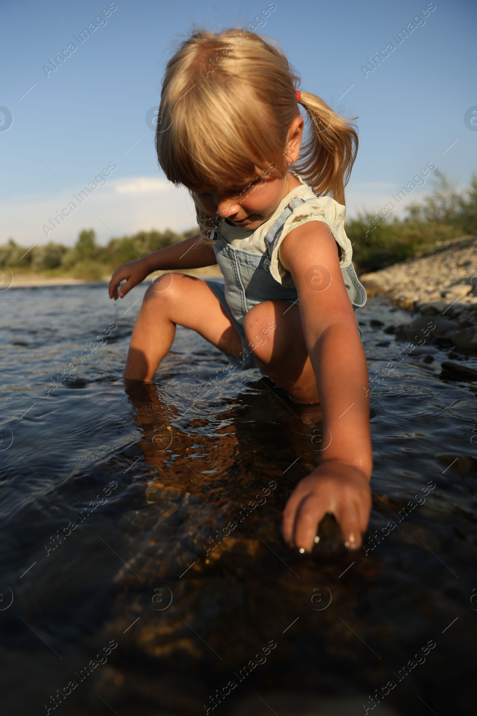 Photo of Cute little girl spending time on river. Child enjoying beautiful nature