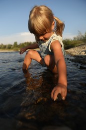 Photo of Cute little girl spending time on river. Child enjoying beautiful nature