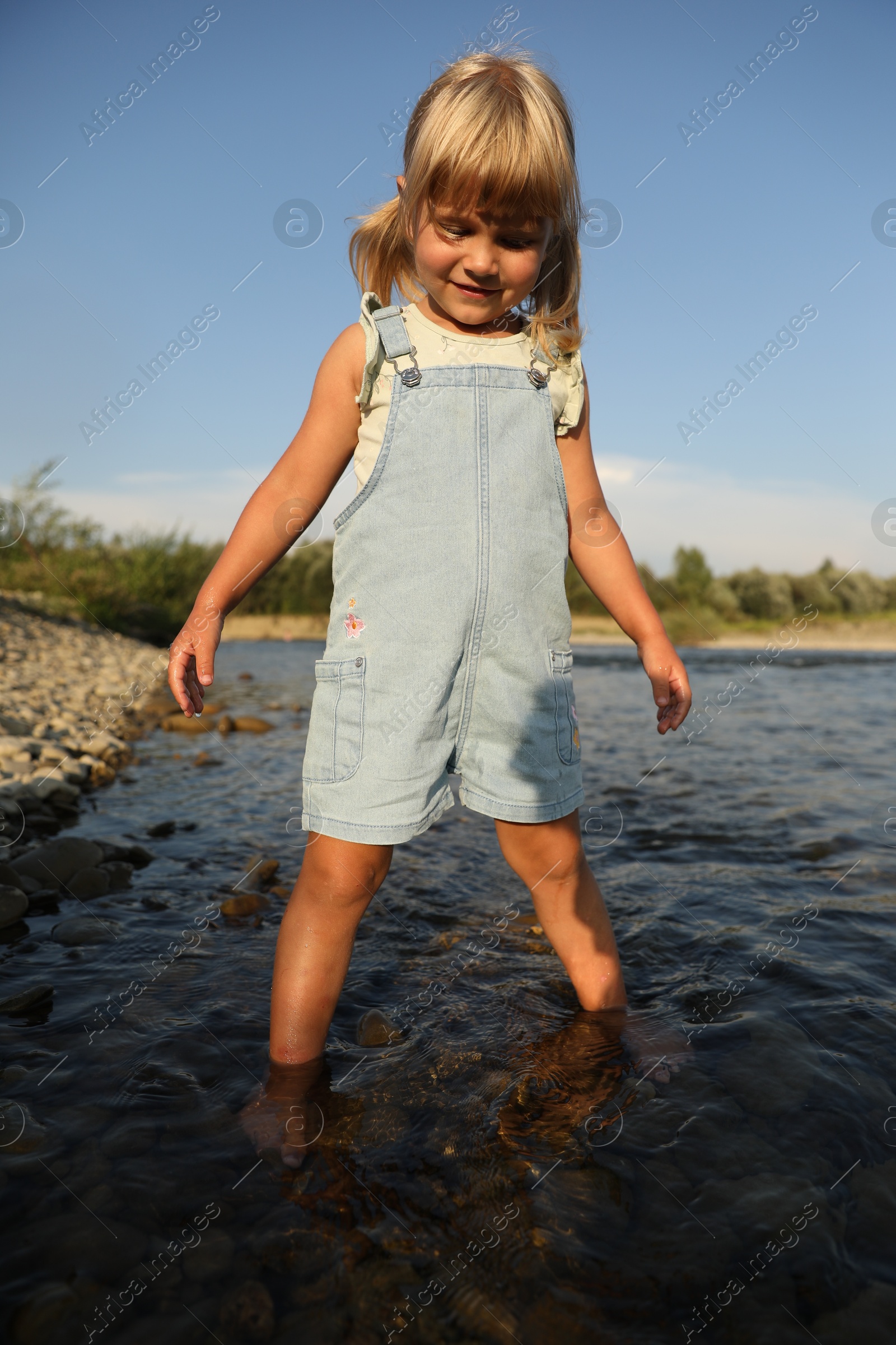 Photo of Cute little girl spending time on river. Child enjoying beautiful nature