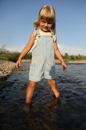 Photo of Cute little girl spending time on river. Child enjoying beautiful nature