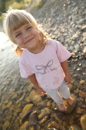 Cute little girl standing in water, above view. Child enjoying beautiful nature