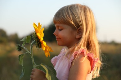 Photo of Little girl with sunflower at meadow. Child enjoying beautiful nature