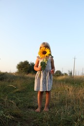 Photo of Little girl with sunflower at meadow. Child enjoying beautiful nature