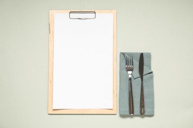 Photo of Clipboard with empty paper for menu design and cutlery on light grey table, flat lay