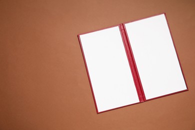 Photo of Hardcover notebook with blank sheets on brown background, top view. Mockup for design