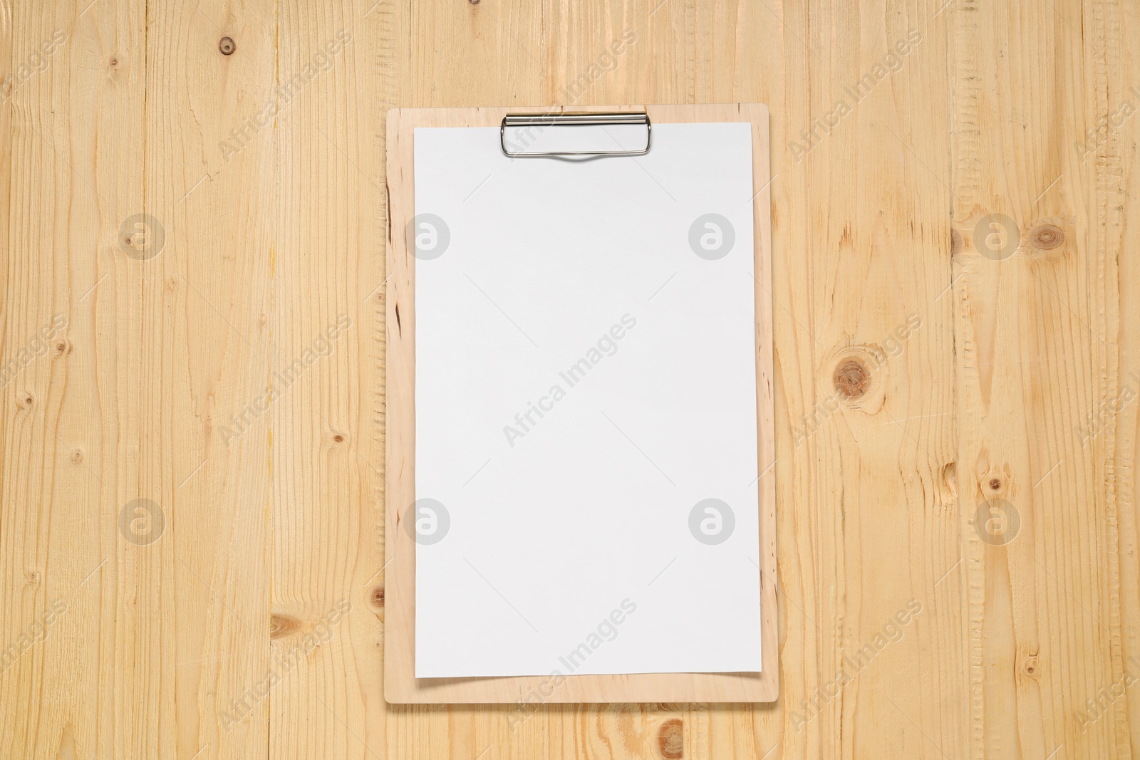 Photo of Clipboard with empty paper on wooden table, top view. Mockup for design