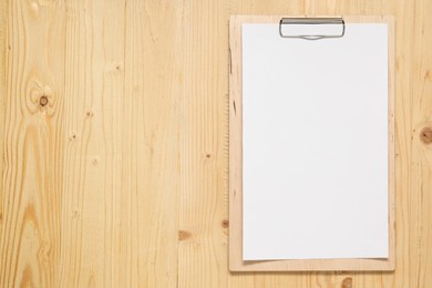 Photo of Clipboard with empty paper on wooden table, top view. Mockup for design