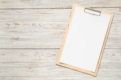 Photo of Clipboard with empty paper on wooden table, top view. Mockup for design