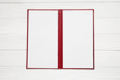 Photo of Hardcover notebook with blank sheets on white wooden table, top view. Mockup for design