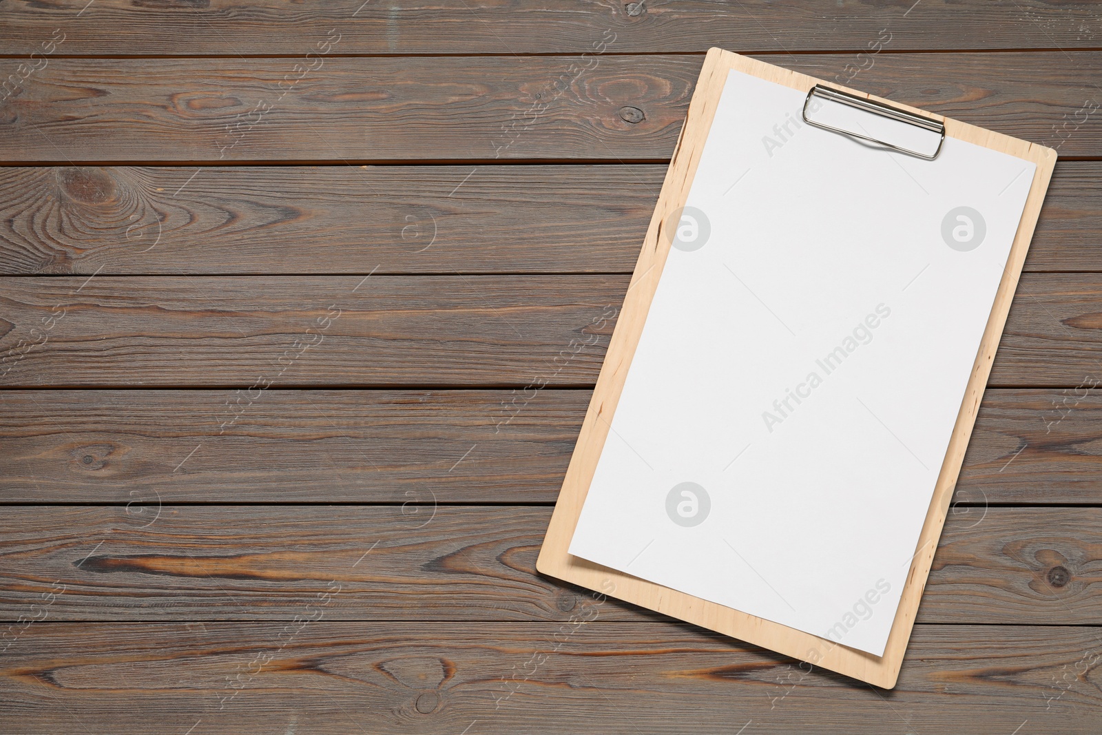 Photo of Clipboard with empty paper on wooden table, top view. Mockup for design