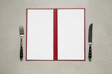 Photo of Hardcover notebook with blank sheets for menu design and cutlery on grey textured table, flat lay