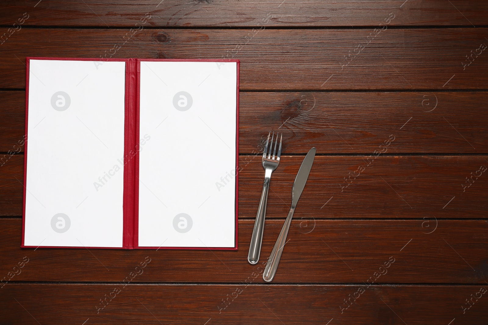 Photo of Hardcover notebook with blank sheets for menu design and cutlery on wooden table, flat lay. Space for text