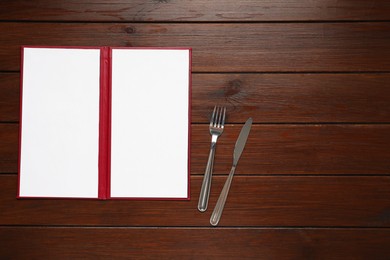 Photo of Hardcover notebook with blank sheets for menu design and cutlery on wooden table, flat lay. Space for text