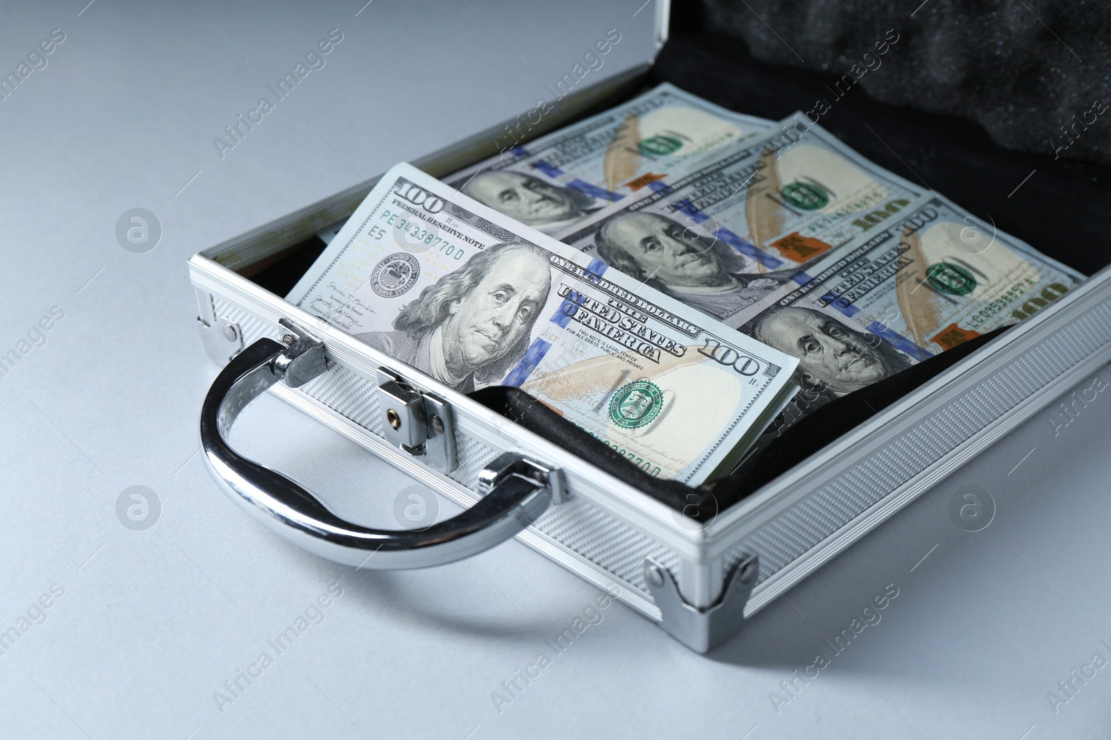 Photo of Metal case full of dollar banknotes on light background