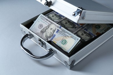 Photo of Metal case full of dollar banknotes on light background