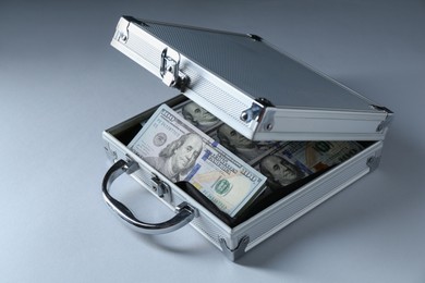 Metal case full of dollar banknotes on light background