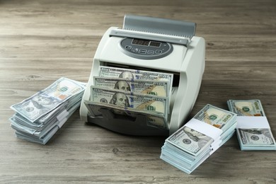 Money counter machine with dollar banknotes on wooden table