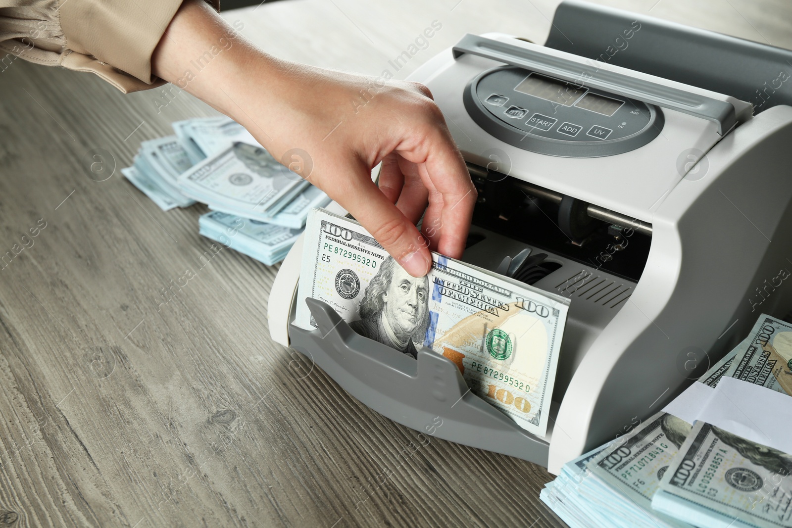 Photo of Woman using money counter machine at wooden table, closeup