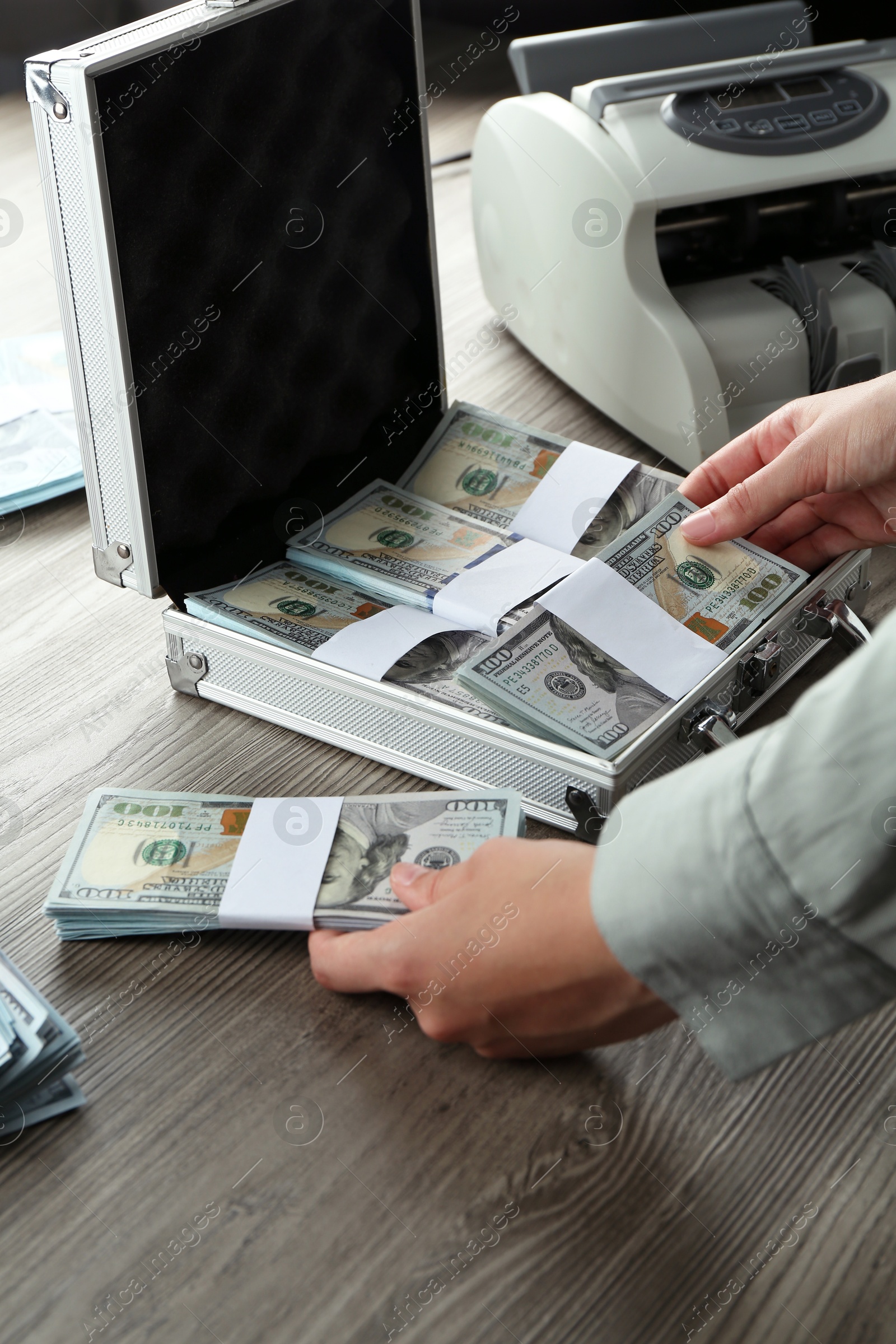 Photo of Woman counting dollar banknotes at wooden table, closeup