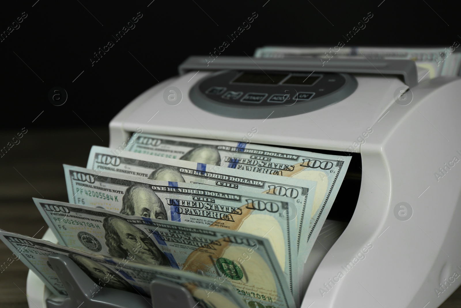 Photo of Money counter machine with dollar banknotes on table, closeup